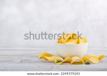 Potatoes Chips. Chips in white bowl good for snack for beer on wooden table. Good for beer festival, pub, restaurant advertising. Copy space for text or logos. Royalty-Free Stock Photo #2249379243