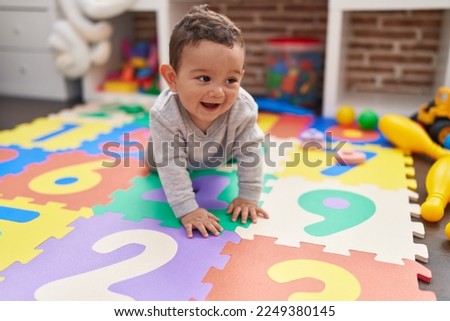Adorable hispanic baby crawling on floor at kindergarten Royalty-Free Stock Photo #2249380145