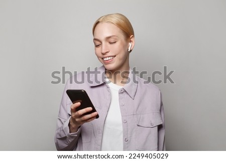 Cute model woman using smartphone and enjoying online communication and social media on white studio wall banner background