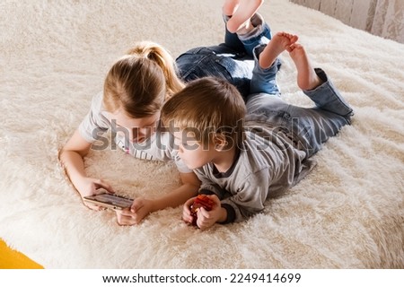 Children are lying on the bed, watching cartoons, playing a game on a smartphone 12.01.23 .Tula, Russia