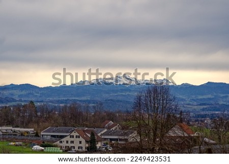 Meadow with apple trees and farm in the background at City of Zürich district Schwamendingen on a cloudy winter day. Photo taken January 14th, 2023, Zurich, Switzerland.