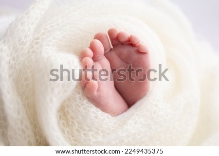 Close-up of tiny, cute, bare toes, heels and feet of a newborn girl, boy. Baby foot on white soft coverlet, blanket. Detail of a newborn baby legs.Macro horizontal professional studio photo.