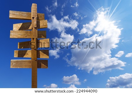 Wooden Sign on Blue Sky with Clouds / Wooden old brown crossroad sign on a blue sky with clouds