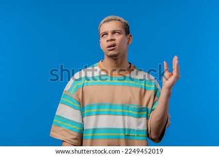 Irritated american man showing bla-bla-bla gesture with hands, rolling eyes on blue background. Empty promises, blah concept. Lier. High quality photo Royalty-Free Stock Photo #2249452019