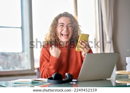 Young happy lucky woman student feeling excited winner holding cellphone using mobile phone winning online, receiving great news or sms offer on smartphone, getting new job celebrating success. Royalty-Free Stock Photo #2249452159