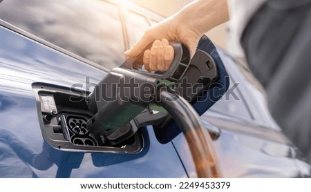 Woman inserting a DC CCS2 EV charging connector into electric car socket at charging station, Hypercharger or Supercharger.  Charge electromobility concept image. Royalty-Free Stock Photo #2249453379
