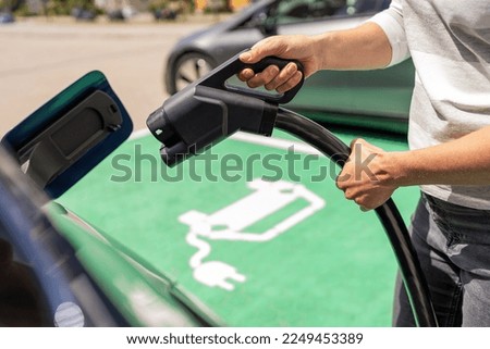 Hand inserting a DC CCS2 EV charging plug into electric car socket at charging station, Hypercharger or Supercharger.  Charge electromobility concept image. Royalty-Free Stock Photo #2249453389