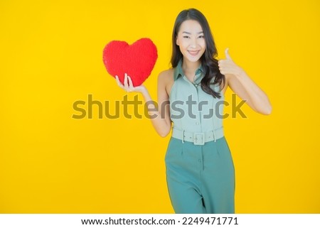 Portrait beautiful young asian woman smile with heart pillow shape on color background
