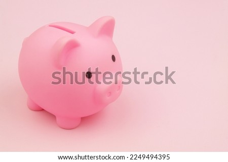 Pink piggy bank on pink background with space for text. Saving money and investments concept.