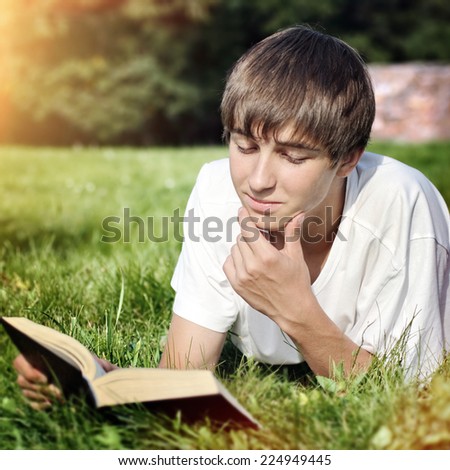 Toned Photo of Happy Teenager reads the Book on the Meadow