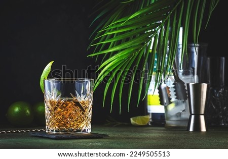 White negroni, alcoholic cocktail with dry gin, white vermouth and herbal aperitif. Dark background, bar tools