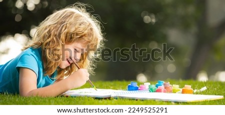 Portrait of smiling happy kid enjoying art and craft drawing in backyard or spring park. Happy child playing outside. Drawing summer theme. Spring and kid. Banner for website header. Royalty-Free Stock Photo #2249525291