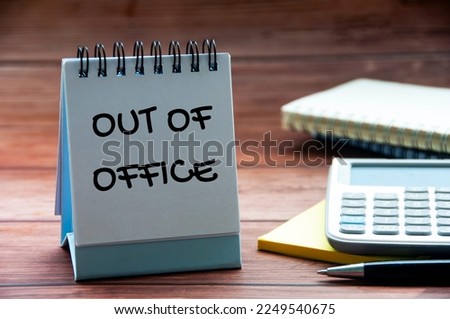Out of office text on calendar desk with notebook, calculator and pen background. Out of office concept Royalty-Free Stock Photo #2249540675