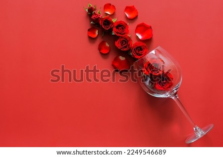 Red roses with empty red wine glass put on red background for Valentines dining concept.