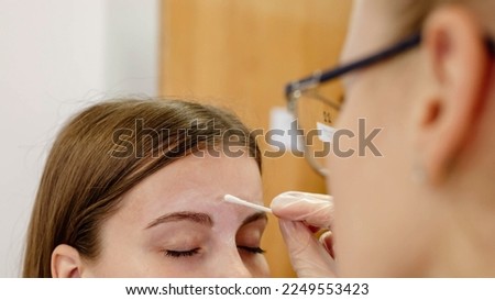 Eyebrow treatment after hot depilation for hair removal. A professional eyebrow specialist helps a girl. Horizontal banner