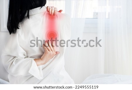 Woman suffering from shoulder blade pain after sleeping on it wrong or having poor posture  Royalty-Free Stock Photo #2249555119