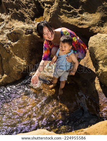Happy mom and baby son splashing water