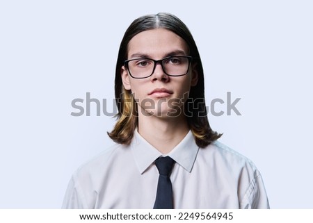 Headshot portrait of serious teenage guy on light studio background