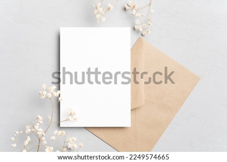 Blank wedding invitation card mockup with envelope and dried flowers. Flat lay, top view, copy space