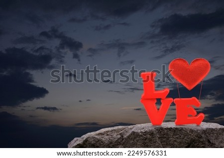 Red love alphabet and fabric heart ballon on rock mountain over sunset sky, Valentines day concept
