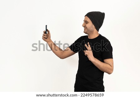 Close up studio photo of a young brown skinned man taking selfie.