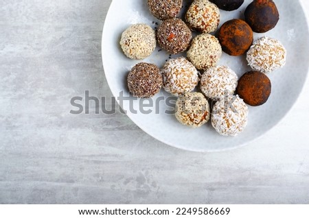Assorted vegan sweets, Delicious Candy Balls with seeds, dried fruit and cocoa powder, Healthy Candies with Chia, Sesame Seeds, Coconut and Truffles on a Plate on grey background