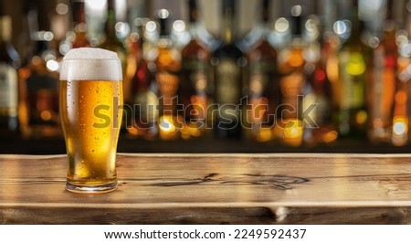 Glass of chilled beer on table and blurred sparkling bar background. Royalty-Free Stock Photo #2249592437