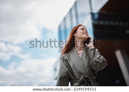 Woman business talking on the phone and smiling with teeth against the backdrop of city buildings, technology and business development concept online