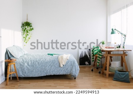 Cozy interior teenage girl room with bed, desk, laptop, photo and adolescence clothes Royalty-Free Stock Photo #2249594913