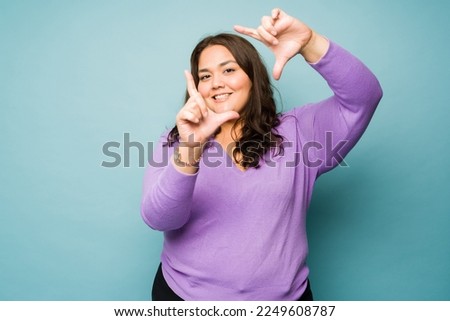 Portrait of an attractive big woman making a frame for a photo while framing taking pictures