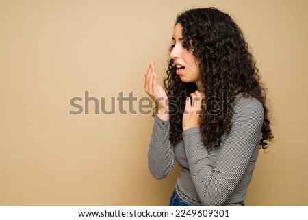 Worried sick latin woman suffering from bad breath or halitosis and poor dental hygiene Royalty-Free Stock Photo #2249609301