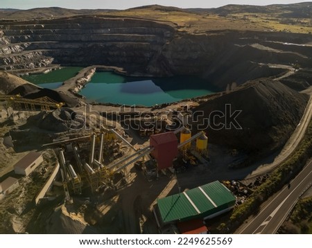 dOpen pit gravel mining. Little lake or pond of unusual shape with a beautiful autumn nature and gravel piles photographed from above with a drone. Real is beautifulefault