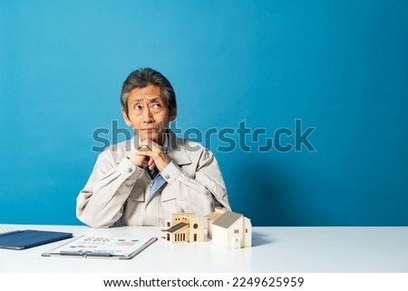 Thinking worker with house model. Architect. Designer. Royalty-Free Stock Photo #2249625959