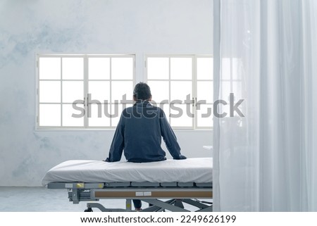 Depressed inpatient sitting on bed in hospital room Royalty-Free Stock Photo #2249626199