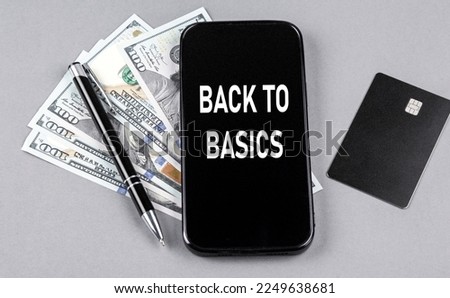Credit card and text BACK TO BASICS on smartphone with dollars and pen. Business concept