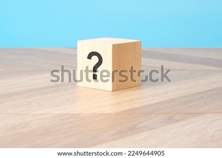 cube with question mark on wooden background, closeup