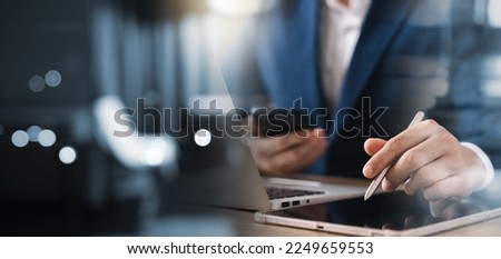 Businessman working on laptop computer and tablet on table at office, working online Use a stylus on a digital tablet screen.