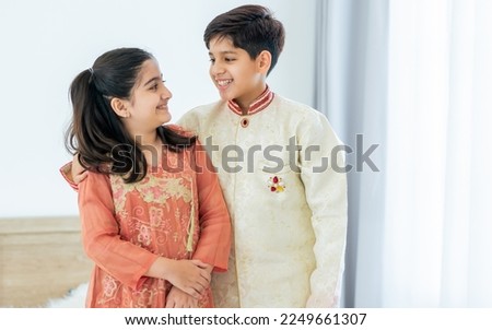Portrait two people Indian siblings, brother, sister hugging with warmth, love, wearing traditional clothes, smiling with happiness in cozy indoor home. Family, Education, Lifestyle Concept Royalty-Free Stock Photo #2249661307