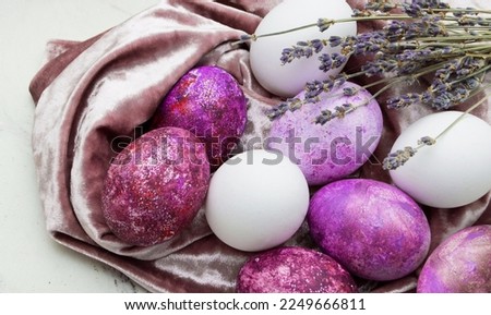 red and white eggs with lavender lie on a velvet fabric on a marble background. Easter card with a place for text in pantone colors