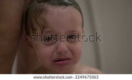 Washing upset baby toddler child in shower bath Royalty-Free Stock Photo #2249675063