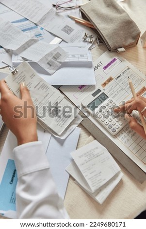 Unrecognizable person calculates bills manages expenses household budget poses at table with papers around checks income analyzes monthly exepnditures. Bookkeeper works from home. Saving and finances Royalty-Free Stock Photo #2249680171