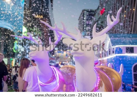 2 white reindeer statue with light decor and fake falling snow in winter at Siam square one, Bangkok, Thailand. Chirstmas festive decoration