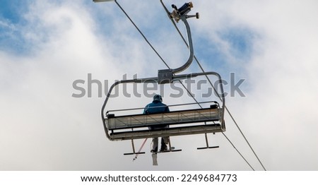 Rear view of a close up of one skier ridding a chairlift up Mount Snow. Royalty-Free Stock Photo #2249684773