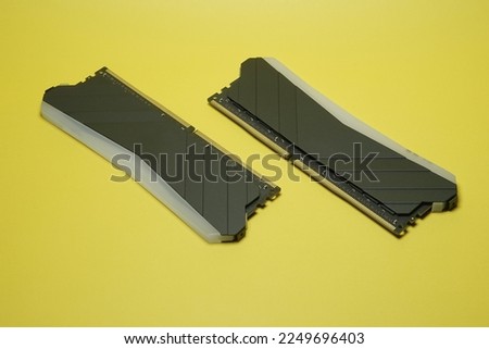 Dimm DDR4 Random Access Memory for desktop computer with black heatsink and RGB LED. Dual Channel RAM on yellow background isolated.