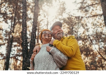 Head shot portrait close up of middle age cheerful people smiling and looking at the the trees of the forest around them. Active couple of old seniors hiking and walking together in the mountain