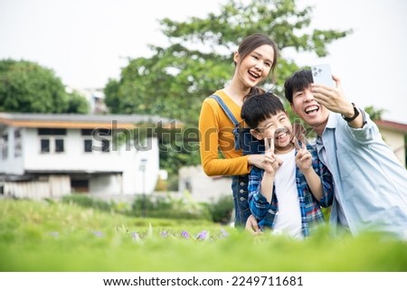 Happy Asian family sitting and taking a selfie using mobile phone outdoors in the garden with fresh air. Beautiful memories. Travel in garden and country farm