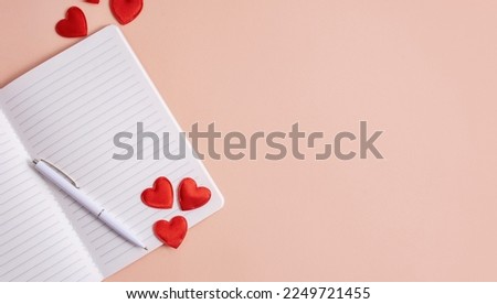 A notebook with a pen and hearts on a light background. Valentine concept, mother's day, birthday card. Flat lay, top view. Copy space.