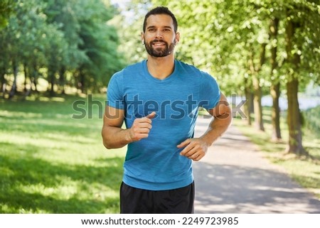 Smiling man running in park at sunny summer day