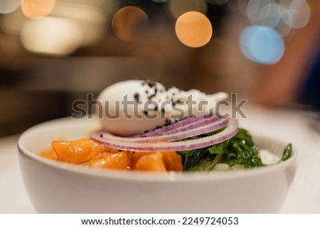 Selective focus Asian salmon poke bowl with blurred background party night lights