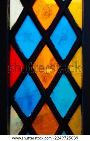 Vertical photo. Colored glass in the form of rhombuses in a metal frame. Window with stained glass. Multicolored Pattern. Kaleidoscope. The concept of a repeating pattern, preservation of antiquity Royalty-Free Stock Photo #2249725039